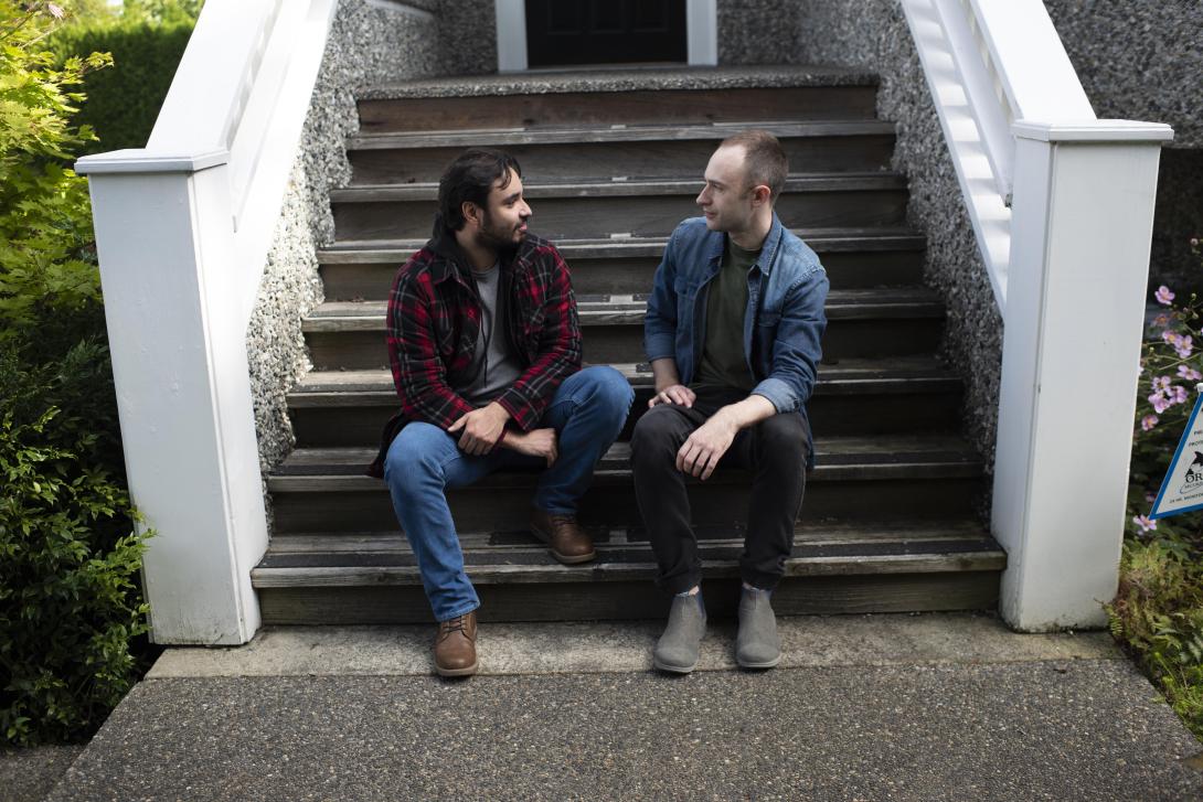 Two men sit on the steps talking.